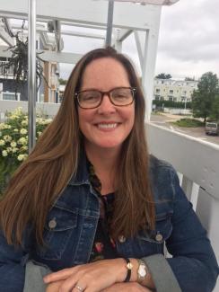 A woman sitting on a porch and smiling at the camera.